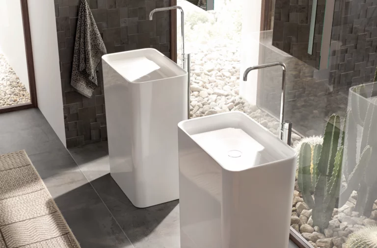 Zwei freistehende, rechteckige Waschbecken aus Stahl-Email mit Armaturen, in modernem Badezimmer vor Glasfront.